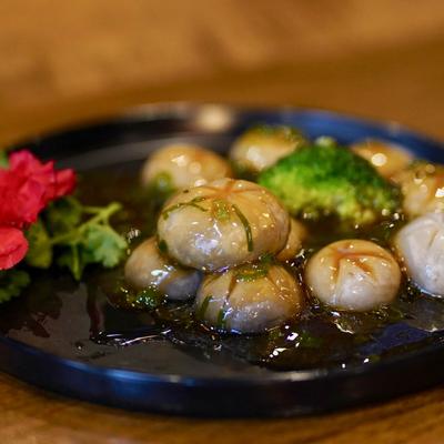 Close-up of mushrooms in sauce with broccoli on a black plate.