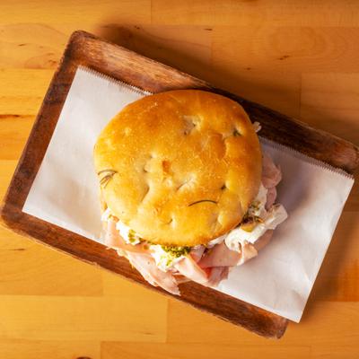 Panini Mortadella Burrata sandwich  on a wooden board.