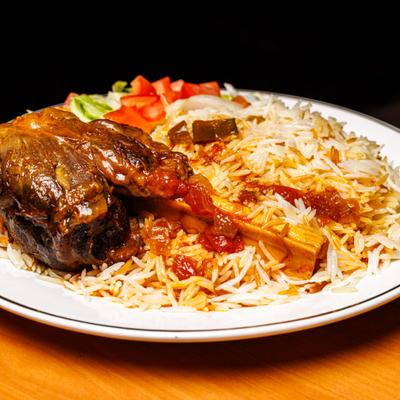 Lamb Shank served over rice with salad on the side.