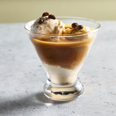 Affogato served  in a martini glass on a gray surface.