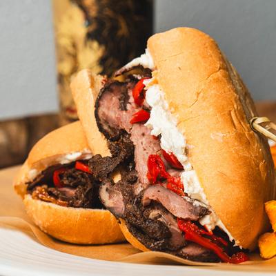 Sliced Roast Beef sandwich with bleu cheese cream and red peppers, served with fries.