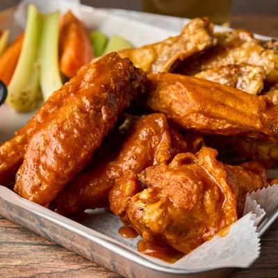 Buffalo wings with celery and carrots on a metal tray.