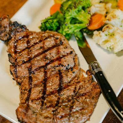 Grilled New York Strip steak paired with a side of mixed vegetables.
