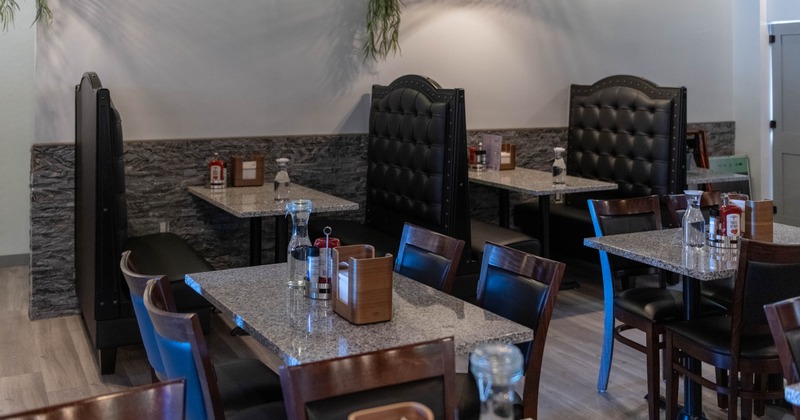 Restaurant interior with granite tables, black leather booths, wooden chairs