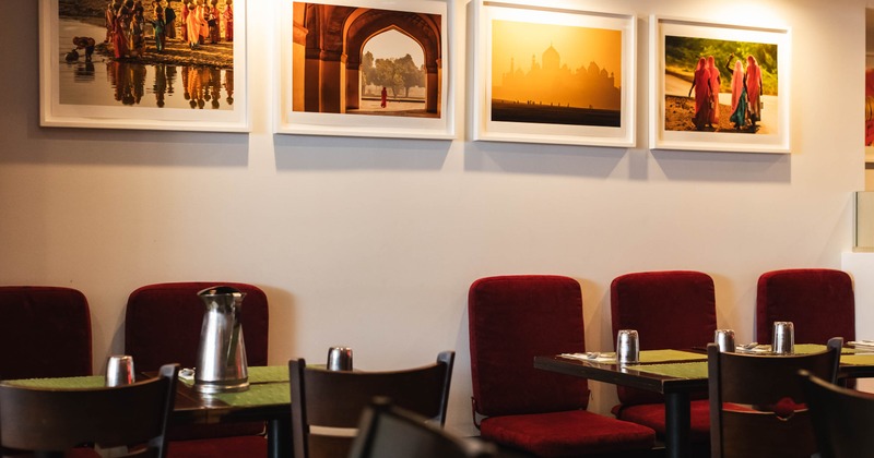 Interior with red chairs and four framed cultural photographs on the wall.