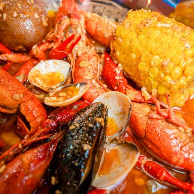Seafood boil featuring a mix of crawfish, clams, corn on the cob, and potatoes.