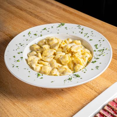 Creamy tortellini pasta beside a plate of sliced sesame-crusted tuna.