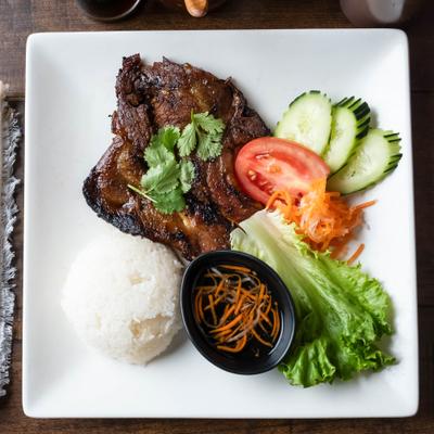 Pork chop served with rice, fresh vegetables and a dipping sauce.