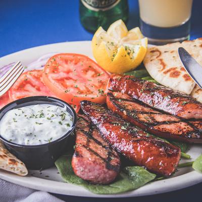 Two grilled sausages served with pita bread