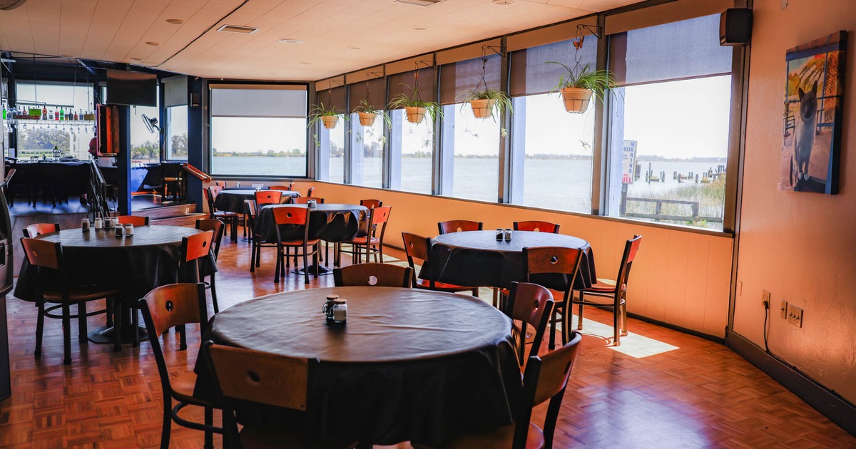 Interior with round tables, wooden chairs, and large windows