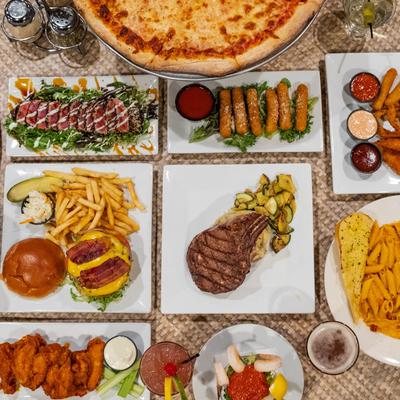 Variety of food plates and cocktails spread on a table.