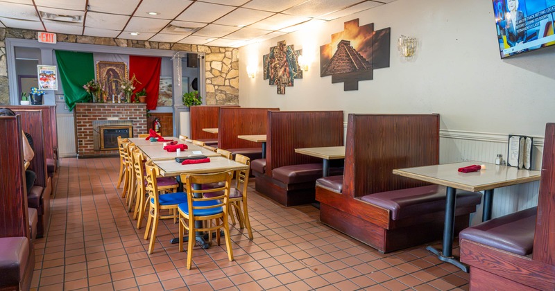 Restaurant dining area with booths, long tables, and Mexican wall art