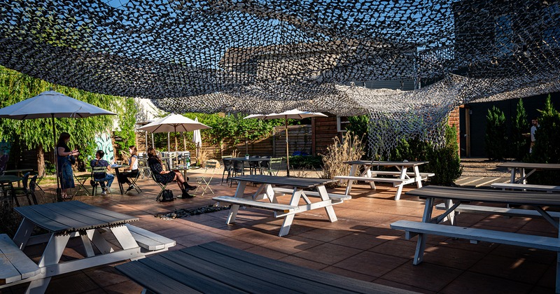 Outdoor seating area, wooden tables with benches, garden parasols and sun shades