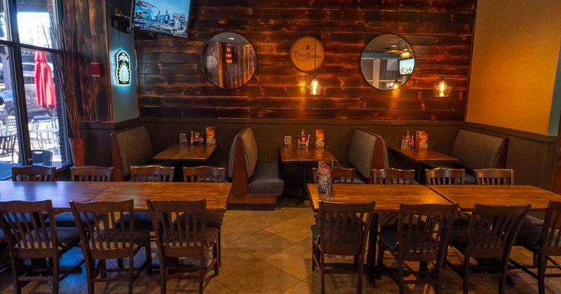 Interior with wooden tables, chairs and booths, featuring warm lighting and a TV.