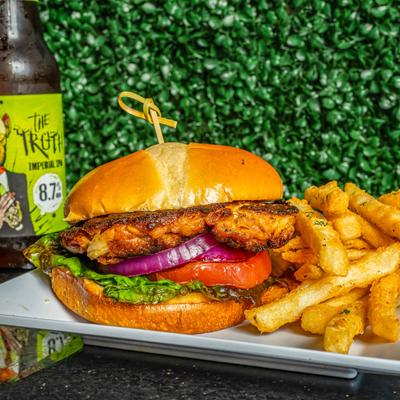 Fried chicken sandwich served with a side of fries and a bottle of The Truth beer.