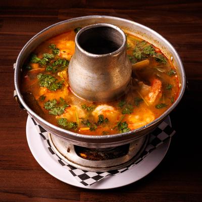 Spicy a sour shrimp soup in a metal hot pot.