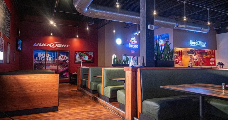Interior, leather padded seating booths with tables, neon signs, wooden flooring