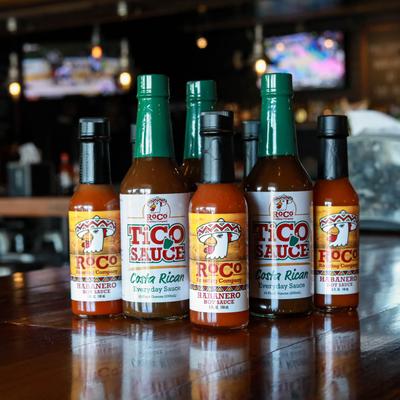 A selection of hot sauces on a wooden counter.