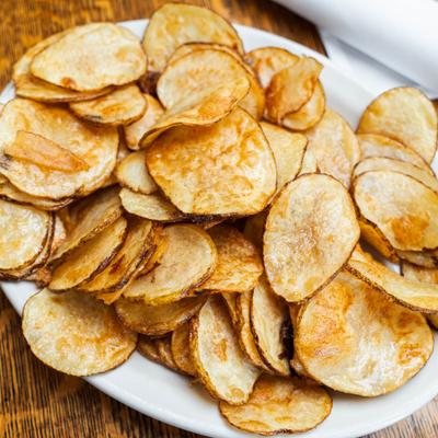 Plate of thinly sliced potato chips, closeup.