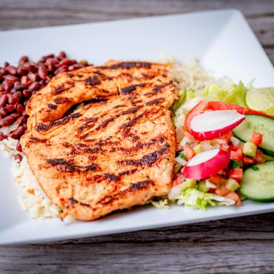 Grilled chicken breast with sides, served on the table.