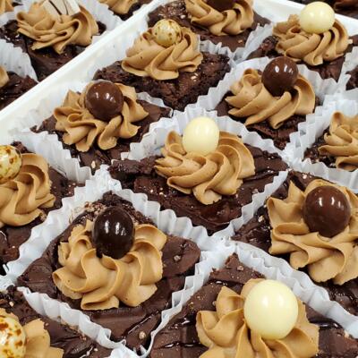 An array of chocolate brownies topped with swirls of caramel frosting.