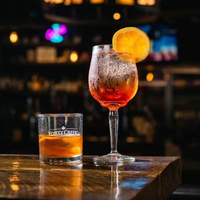 Old Fashioned and Aperol Spritz on a wooden table.