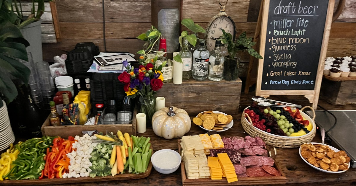 A colorful buffet table with fresh veggies, cheese, and meats arranged on wooden boards