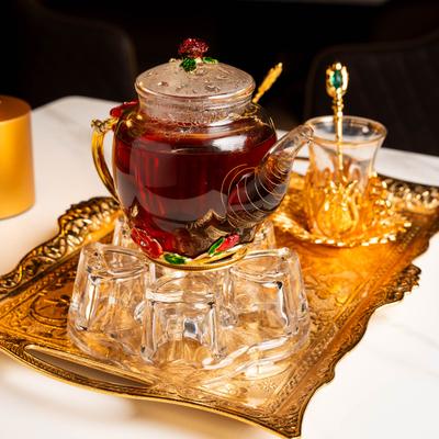 Glass teapot on a gold tray with glass tea cups.