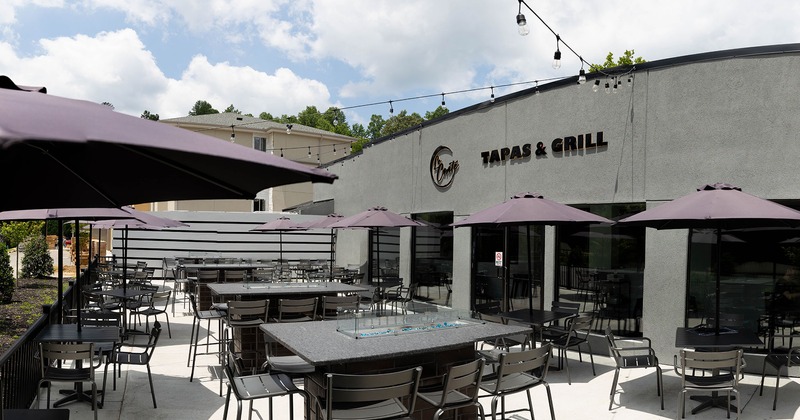 The outdoor area, patio with tables, chairs, and sunshades umbrellas