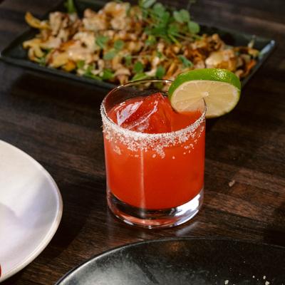 Margarita with salted rim and a lime wheel sits on a dining table.