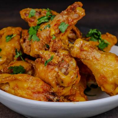 A bowl of fried chicken wings garnished with cilantro.