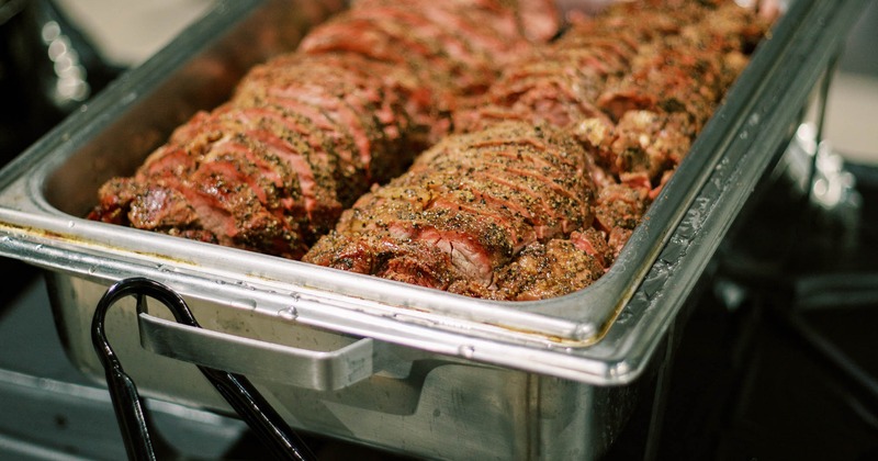 Catering dish filled with sliced pepper-crusted smoked brisket