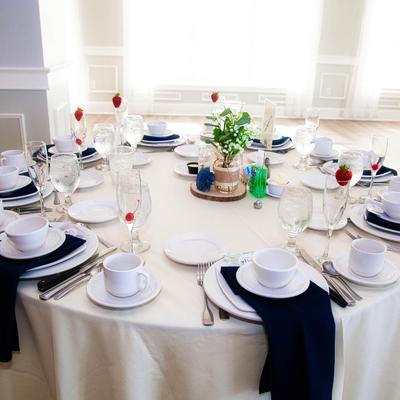 Dining table with black napkins, plates, utensils, glasses, and cups.