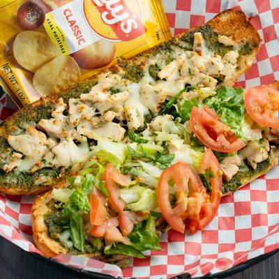 Hot Ham and Cheese sandwich topped with lettuce and tomato, served with a bag o chips.