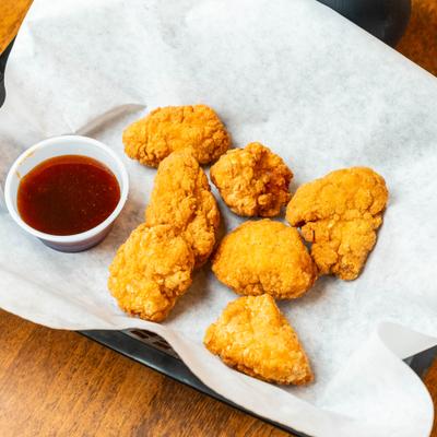 Chicken Nuggets served in paper-lined basket with a dipping sauace.
