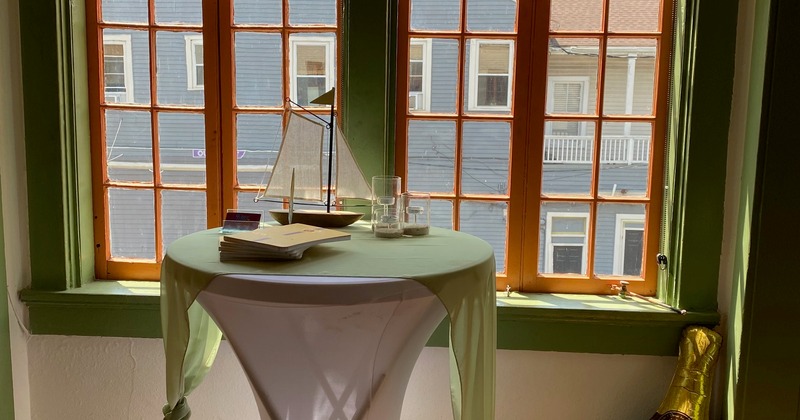 A cocktail table displaying a book and a sailboat model, positioned in front of a window