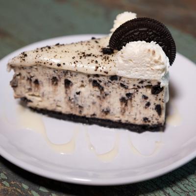Oreo Cheesecake decorated with a whipped cream dollop and a whole cookie.