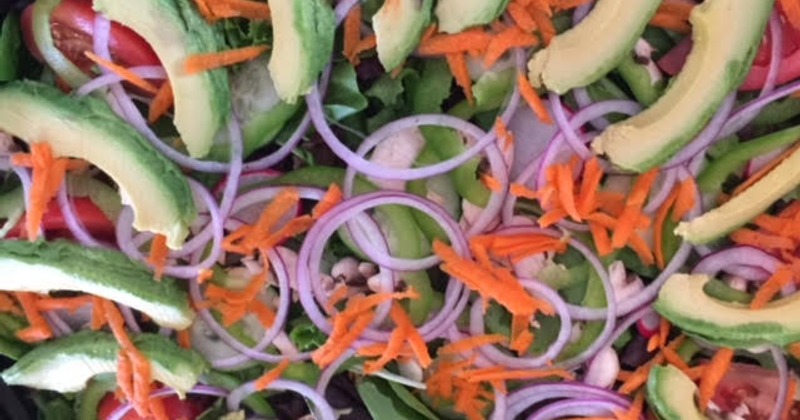Mixed greens salad with avocado, onions, bell peppers, and carrots
