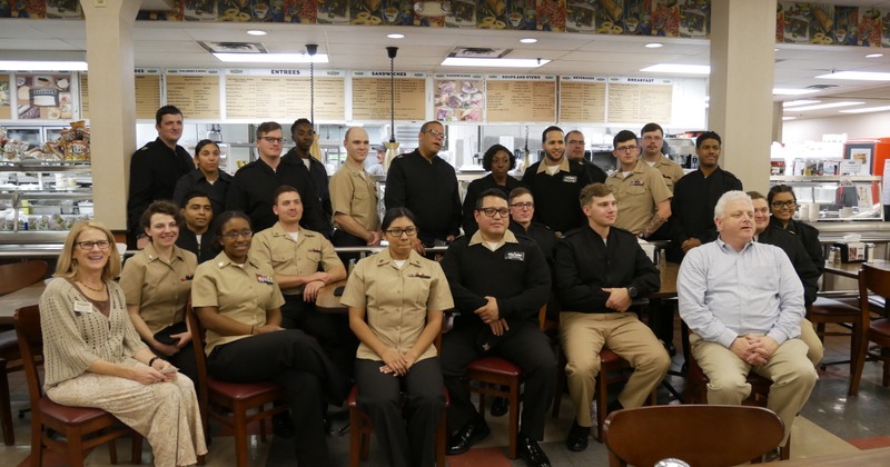 Group of people standing and sitting on chairs