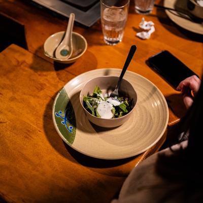 A bowl of salad served to a guest at a table.