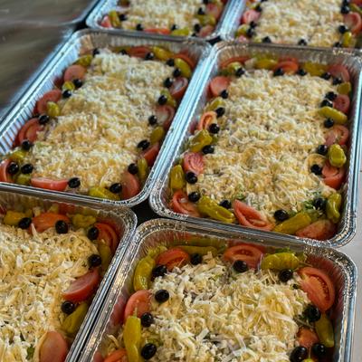 Salads served in disposable aluminum catering trays.