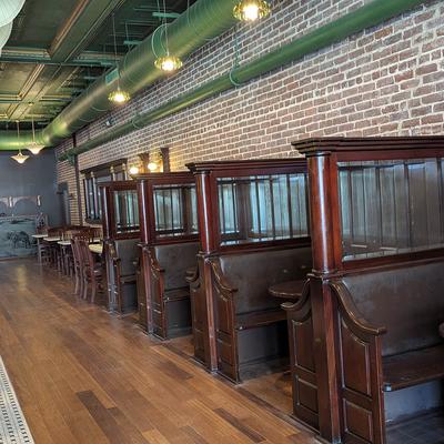A vintage-style restaurant interior with wood booths alongside an exposed brick wall.