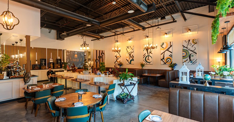 Interior, teal chairs, leather booths, abstract artwork, plants, exposed industrial-style ceiling