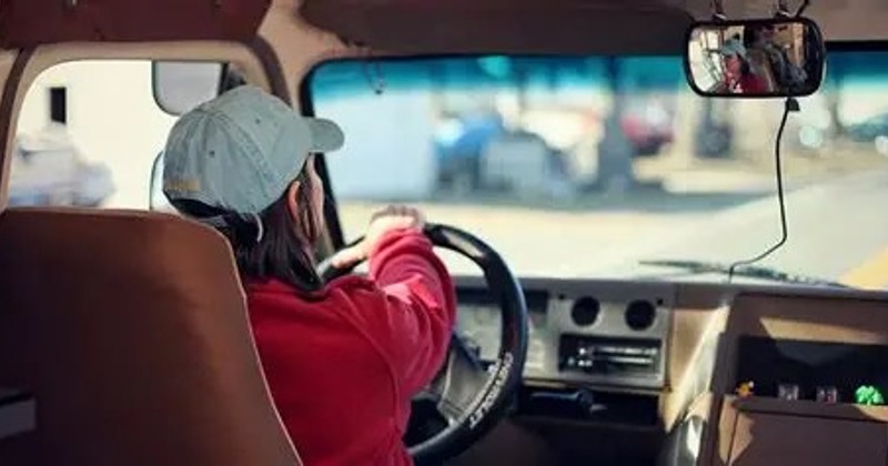 A chef is using a large, cleaver-style knife to chop vegetables on a wooden cutting board