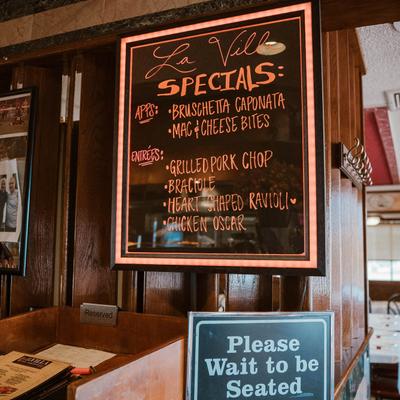 Hostess stand with a specials board on a wall.