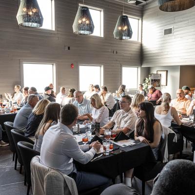 Restaurant guests dining beneath decorative pendant lights in a spacious room.