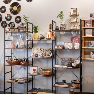 Gift shop shelves with various items and prices, vinyl records on the wall.