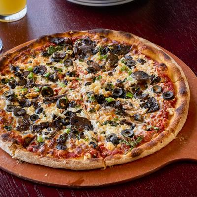 Veggie pizza topped with mushrooms, olives and herbs.