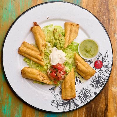 Taquitos, served with lettuce, sour cream, pico de gallo, and guacamole.