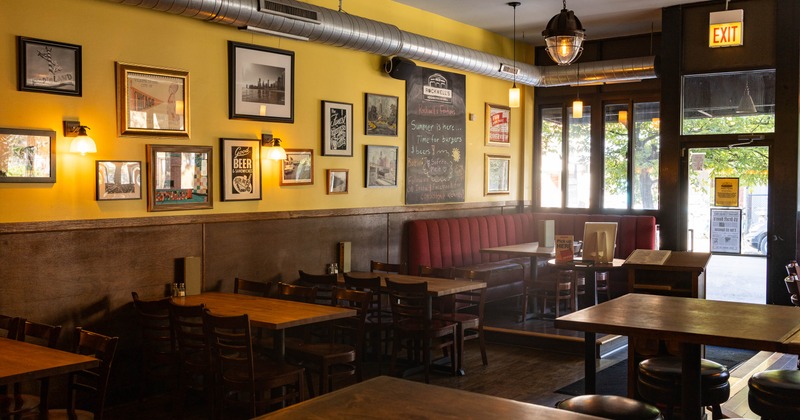 Inside, dining room with framed artwork, a chalkboard menu, wooden tables, red booths